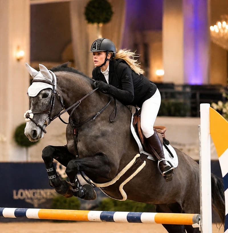 Harriet Smith jumping a chestnut horse over a coloured oxer at an indoor competition