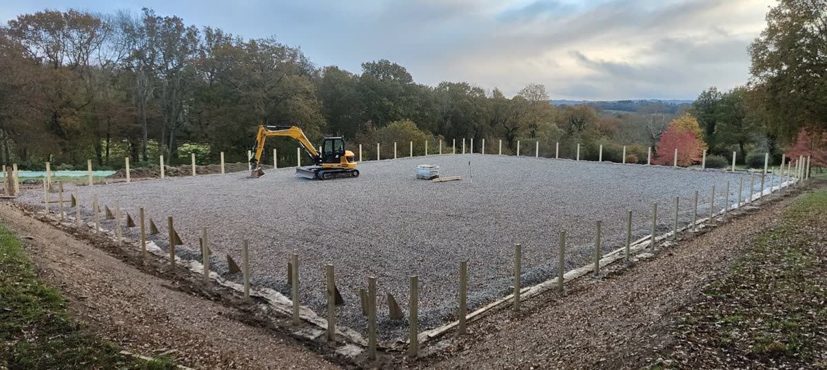 Stone sub-base spread and levelled across a new arena with an excavator at work